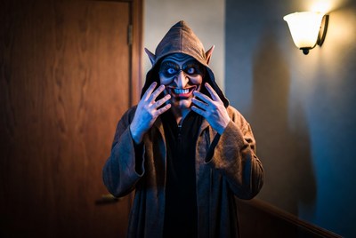 Man in goblin mask with hands on face