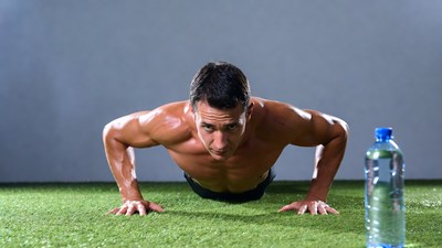 Muscular man doing pushups on grass