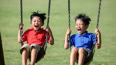 Asian boys laughing on swings