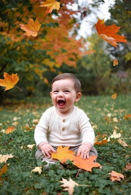 Baby laughing in autumn leaves