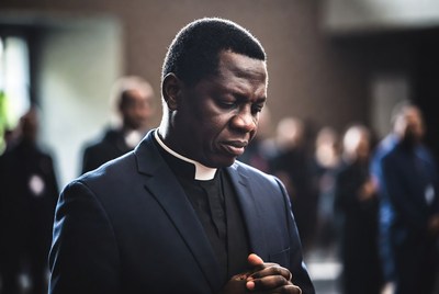 African priest praying in church
