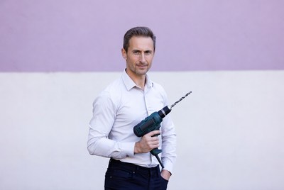 Man holding drill against purple wall