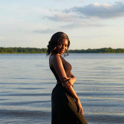 African woman standing by lake sunset