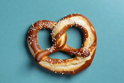 Fresh salted pretzel on blue background
