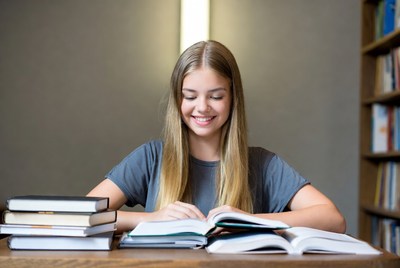 Young woman studying books at library table