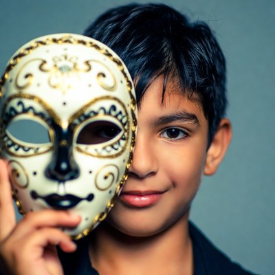 Boy holding ornate masquerade mask