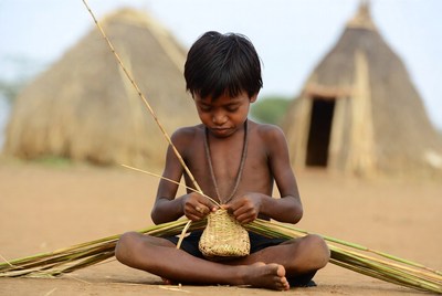 Young boy weaving basket with reeds