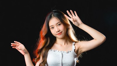 Asian girl waving hands on black background