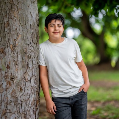 Boy leaning against tree smiling