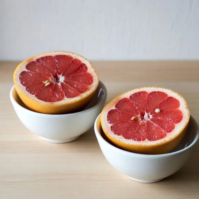 Two Halved Grapefruits in White Bowls