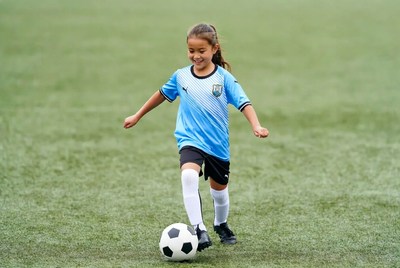Girl kicking soccer ball on field