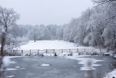 Snowy Field with Frozen Pond and Fence