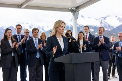 Blonde woman speaking at podium with applauding crowd