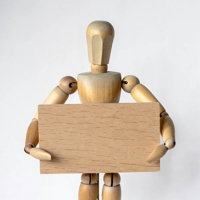 Wooden mannequin holding blank sign