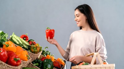 Asian woman holding red bell pepper