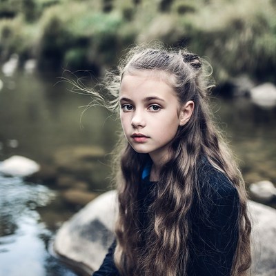 Girl sitting by riverside stream