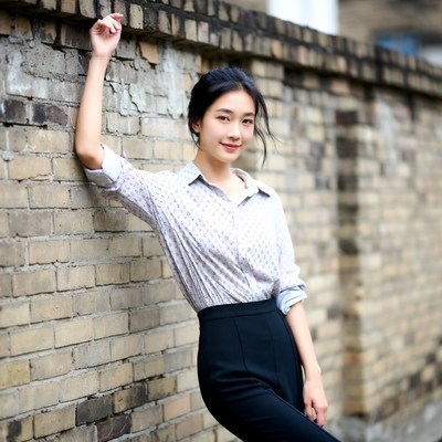 Asian woman leaning against brick wall