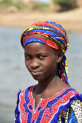 African girl in colorful headwrap by river
