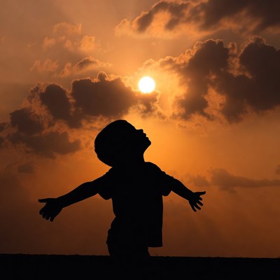 Boy silhouette arms outstretched sunset