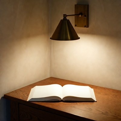 Open book on wooden table under wall lamp