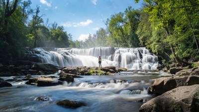Woman standing before cascading waterfall