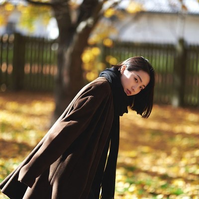 Asian woman in brown coat autumn leaves