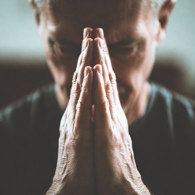 Elderly man praying with hands