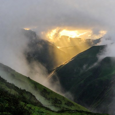 Sun rays over misty green mountains