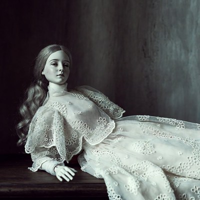 Doll in white lace dress lounging