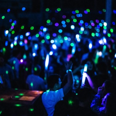 Crowd Dancing with Glow Sticks at Night
