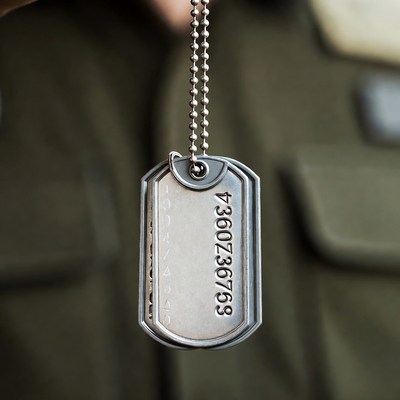 Military dog tag held by hand