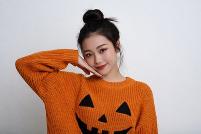 Asian woman in pumpkin Halloween sweater