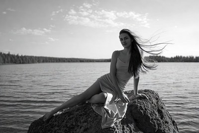 Woman in dress on rock by lake