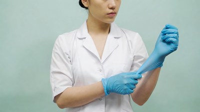 Asian woman putting on blue gloves