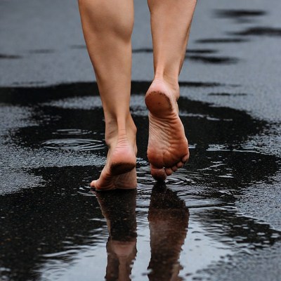 Barefoot woman walking wet pavement