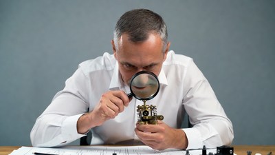Man examining antique clock with magnifying glass