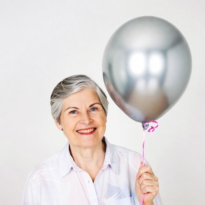 Smiling senior woman holding silver balloon