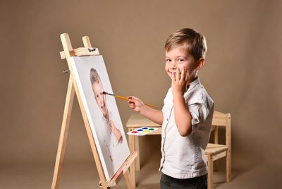 Boy painting self-portrait on easel