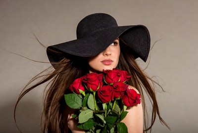 Woman holding red roses with wide-brim hat