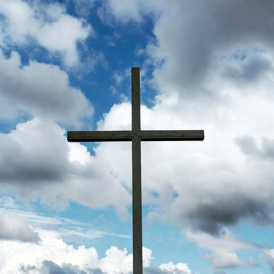 Wooden Cross in Cloudy Blue Sky
