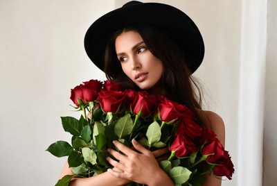 Woman holding red roses in black hat