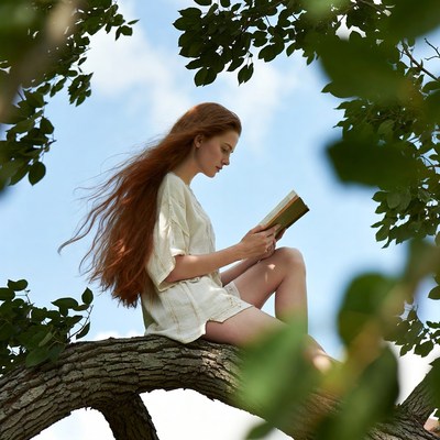 Redhead woman reading book in tree