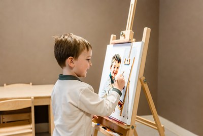 Boy painting self-portrait on easel