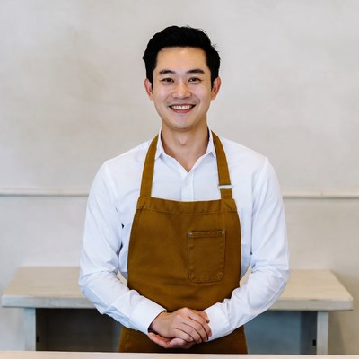 Asian man in brown apron smiling