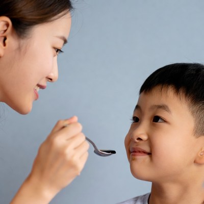 Asian mother feeding boy spoon