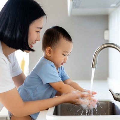 Asian mother teaching baby to wash hands