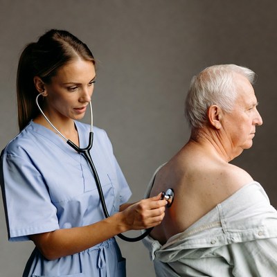 Nurse checking elderly man's heartbeat