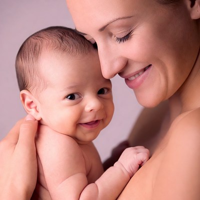 Mother holding smiling newborn baby