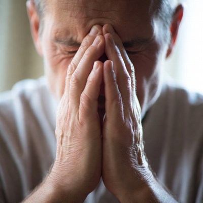Elderly man rubbing forehead in distress
