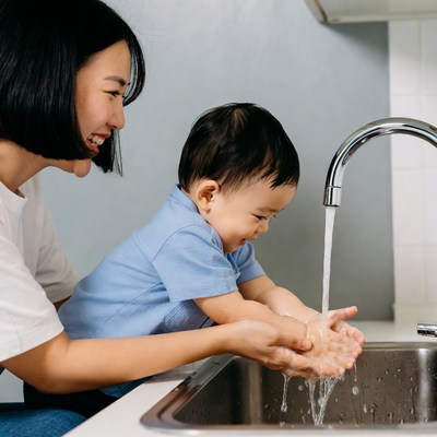 Asian mother helping baby wash hands